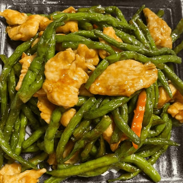 King's Chinese stir-fried chicken and green beans, with a hint of orange pepper, in a dark dish.